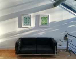 A black couch on the wall over it, two framed watercolor paintings. Anna Slobodnik, 2018. 