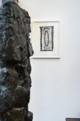 In the front: a detail of a big metall sculpture, in the back a framed lithograph of a black and white carpet. Anna Slobodnik, 2018. 