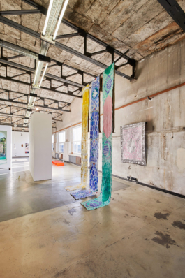 Installation view of three canvases infront of a work on paper. 