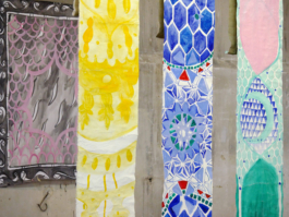 Detail view of three ornamented canvases in front of an patterned work on paper. 