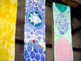 Detail view of three long canvases in yellow, blue and green. 