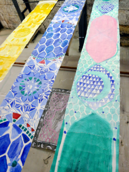 Detail view of three long canvases in yellow, blue and green. 