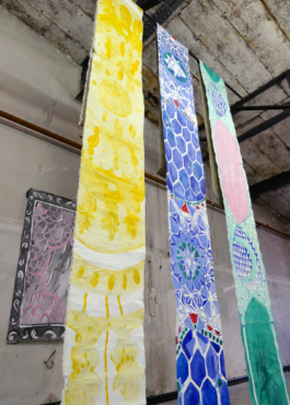 Detail view of three long canvases in yellow, blue and green. 