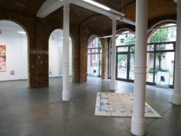 View of a room with columns and big windows, a drawing is laying on the floor. 