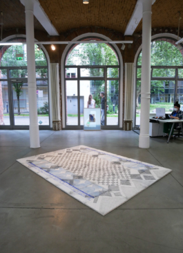 View of a drawing on the floor and behind it windows and people standing on the other side of it. 