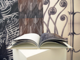 An open book with floral photographies lying on a plinth. 