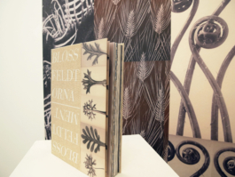 Close up on the book Blossfeldt and the ornament infront of a floral wallpaper. 