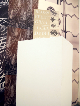 Close up on the book Blossfeldt and the ornament in front of a floral wallpaper. 