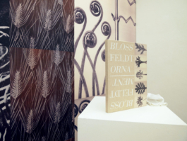 Close up on the book Blossfeldt and the ornament in front of a floral wallpaper. 