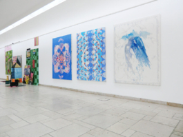 Three bluish paintings with carpet patterns on them. On the left of them the colorful works of another artist. UdK Berlin 2016. 