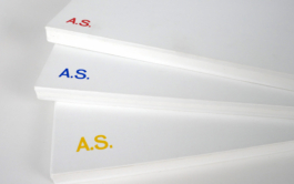 Three white books with red, blue and yellow letters on them over each other. 