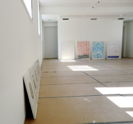 A big room with small prints on the left wall and four big paintings leaned against the back wall. Anna Slobodnik 2016. 