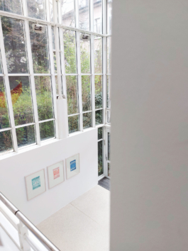 View down on a sun room with three framed stone prints in red, blue and green. 