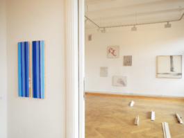 View through an arc. On the left a blue painting. In the next room several paintings and small sculptures on the floor. Galerie Pankow 2015. 