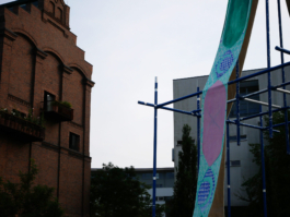 A green ornamented painting on a raft in front of houses. 