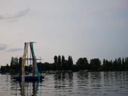 A raft with a yellow and a green painting, trees behind it. 