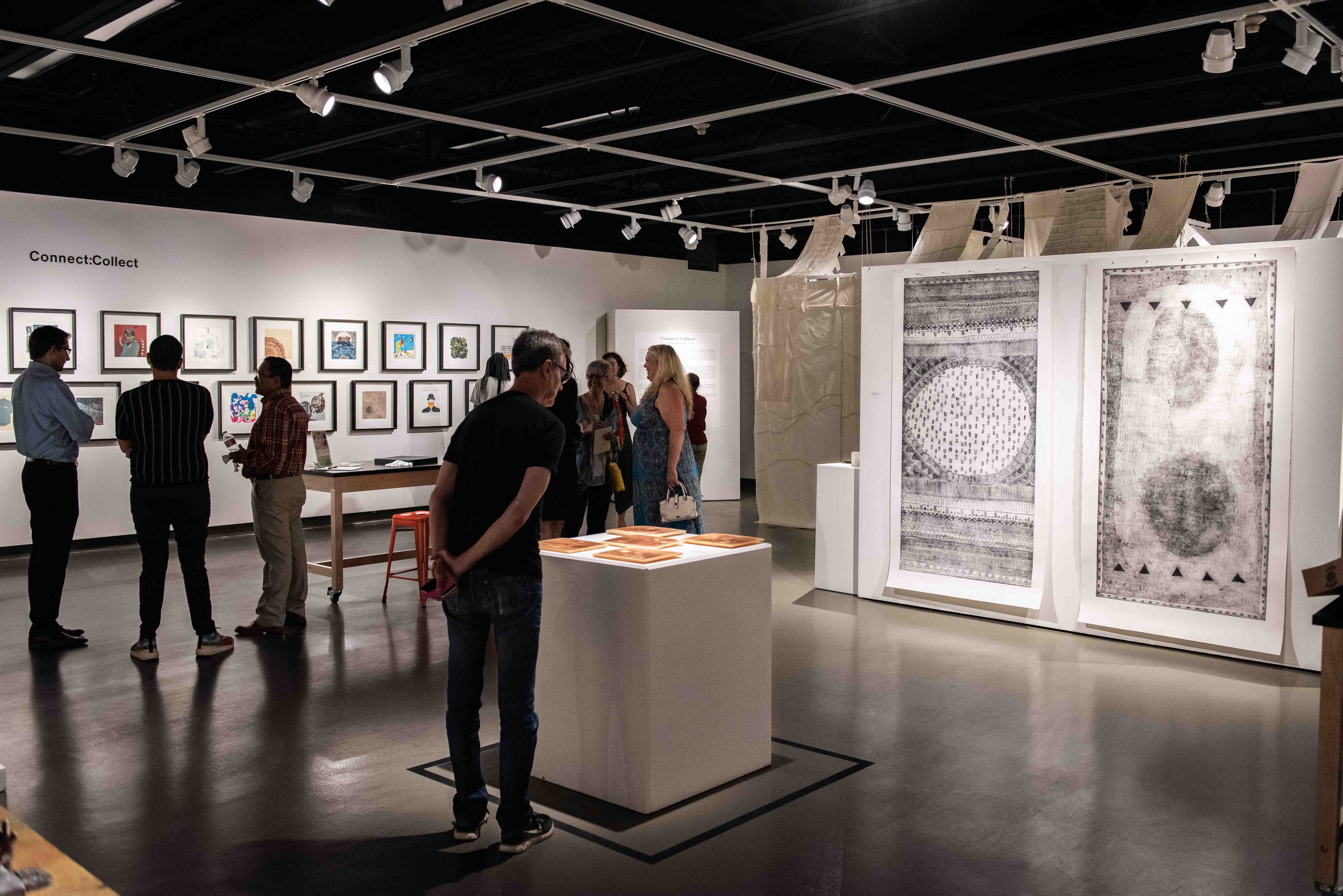 Exhibition view with two large format prints and many colorful images in the background. 
