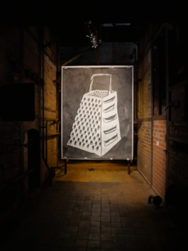 A painting of grater in black and white hanging in a dark brick room. 