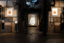 Exhibition view of a big painting of a grater and two smaller prints. 