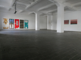 View of an exhibition space. In the far left corner you see the paintings of Anna Slobodnik (five colorful doors) on the wall. 