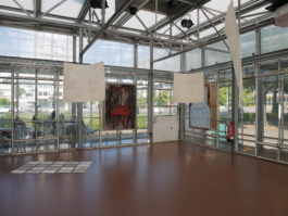 Installation view of the exhibition Perceiving Painting with two paintings of chairs by Anna Slobodnik in the background and paper works of Lisa Ballmann hanging from the ceiling and her works out of concrete on the floor. 