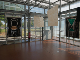 Two paintings of two chairs, one of them green and the other one beige. Inbetween them two paper drawings. 