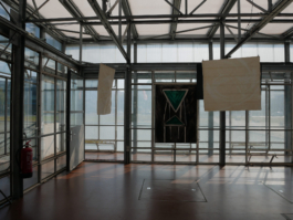A painting of a green chair and two drawings of paper in a glass building. 