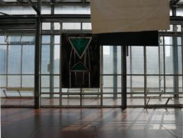 A painting of a green modern chair infront of a glass wall with light shining through it and throwing shadows on the floor. 