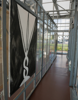 A painting of a glass in black and white on the left side. On the right a passage with glass walls. 