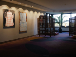 View of a hotel floor with room deviders in front of the windows and two paintings to the left. 
