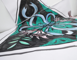 A close up of a big painting of a scarf in black, green, blue and red on paper. 