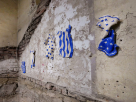 Exhibition view of five ceramic works depicting kitchen towels with different patterns on them. 