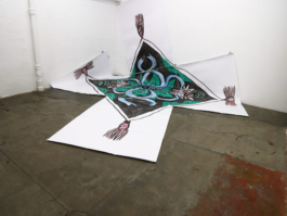 A big painting on paper with a scarf on it, the scarf has red flowers, green leaves and blue ribbons on it. 