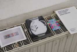 Flyers and postcards of the exhibition on a heater. 