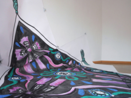 A close up of a big painting of a scarf in black purple and turquoise on paper. 