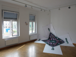 Installation view of a big painting of a scarf in black purple and turquoise and a ceramic of a kitchen towel on the wall. 