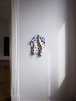A ceramic of a kitchen towel with blue dots hung up on a wall. 