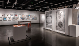 Exhibition view with two large format prints and many colorful images in the background. 