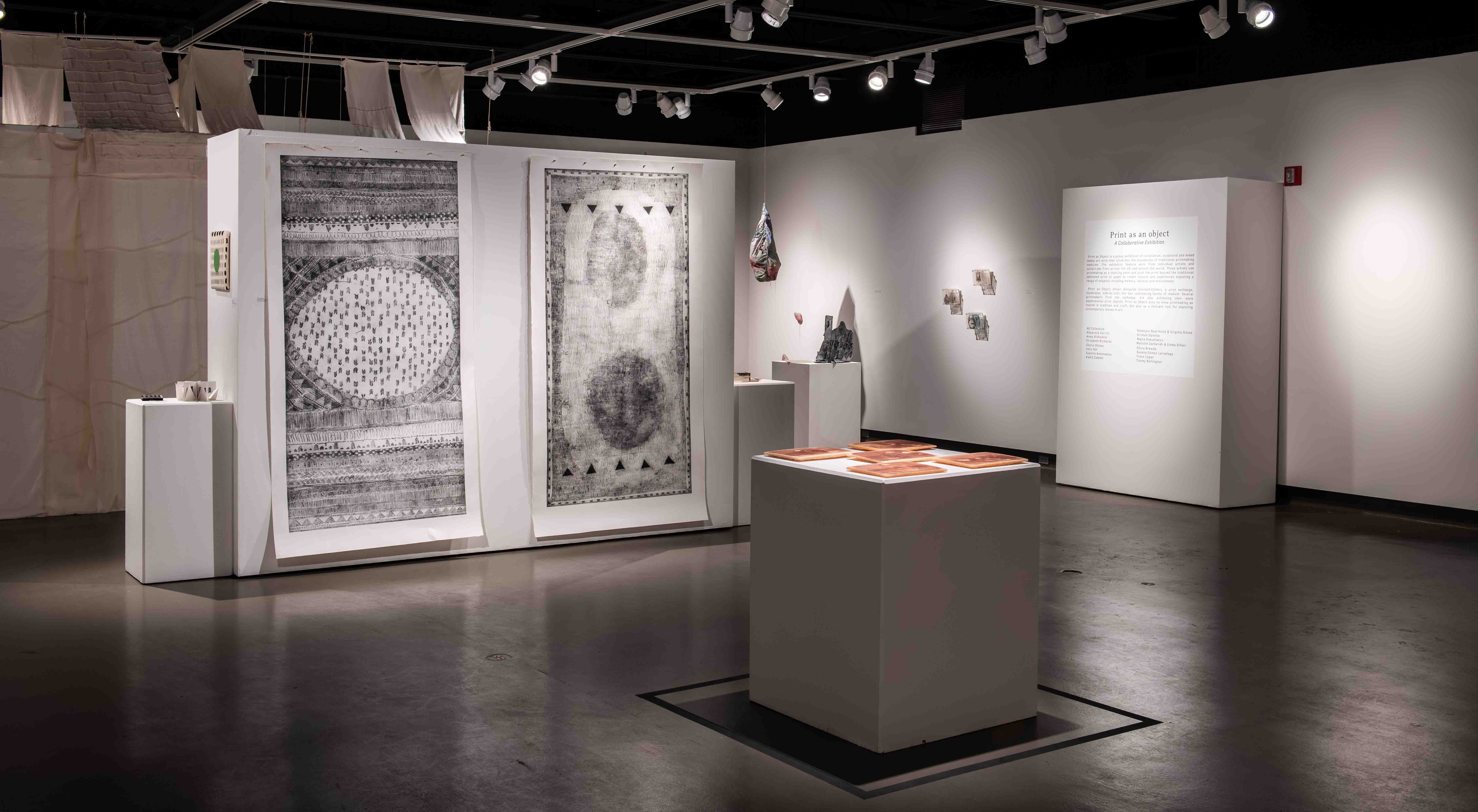 Exhibition view with two large-format prints and in front of them a platform with terracotta-colored plates. 